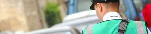 A traffic warden checking car details